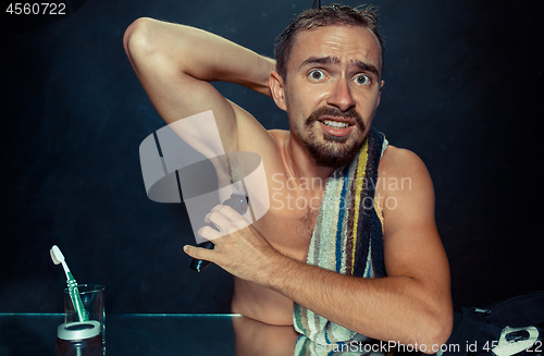 Image of Photo of handsome man shaving his armpit