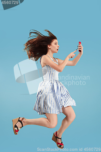 Image of Full length of pretty young woman with mobile phone while jumping