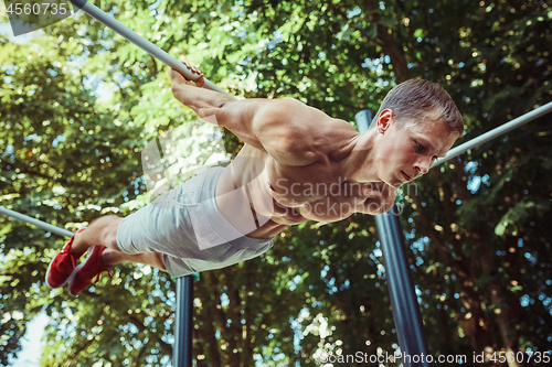 Image of Athlete doing exercises at stadium at park