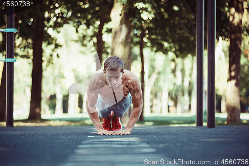 Image of Athlete doing exercises at stadium at park