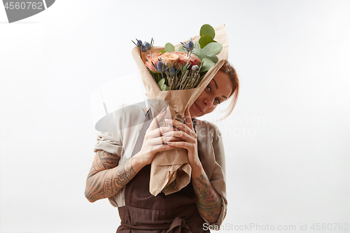 Image of Smiling girl holds greeting bunch from fragrant beautiful flowers living coral colored on a gray background. Copy space. Concept Mother\'s Day.