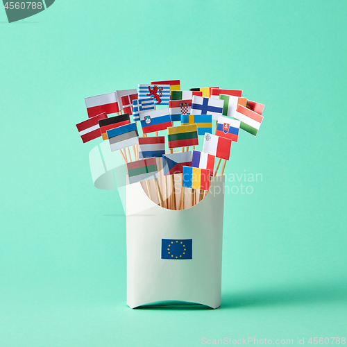 Image of Set of different paper flags in cardboard box decorated with EU sign on green background with copy space. Economic, Political Union of European States