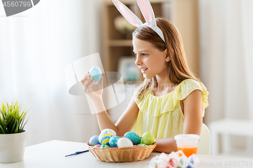 Image of happy girl with colored easter eggs at home