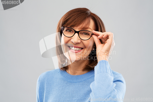 Image of portrait of senior woman in glasses over grey