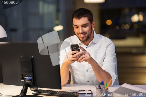 Image of businessman with smartphone and computer at office