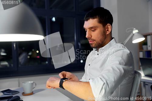 Image of businessman using smart watch at nigh office