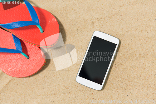 Image of smartphone and flip flops on beach sand