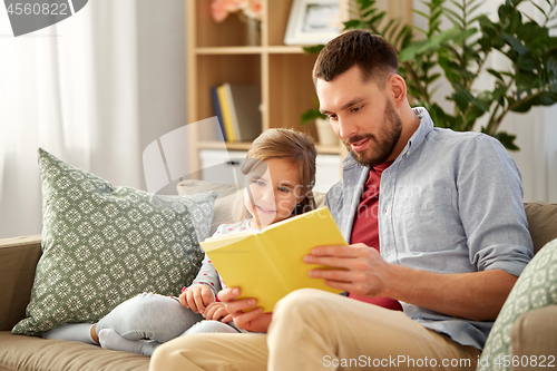 Image of happy father and daughter reading book at home