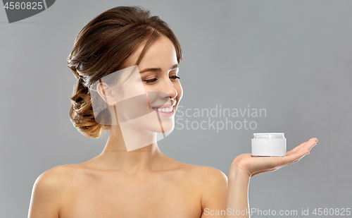 Image of happy young woman holding jar of cream