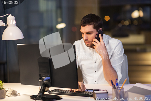 Image of businessman calling on smartphone at night office