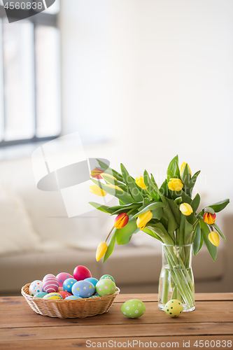 Image of colored easter eggs in basket and flowers at home