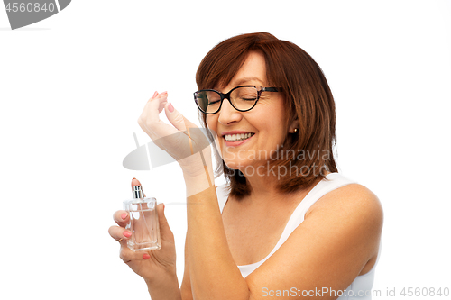 Image of senior woman smelling perfume from her wrist