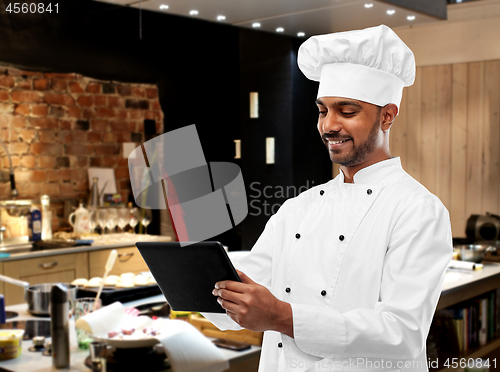 Image of happy indian chef with tablet computer at kitchen