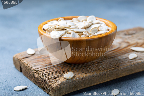 Image of Unpeeled pumpkin seeds in a wooden bowl.