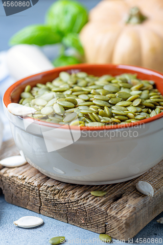 Image of Raw pumpkin seeds in a ceramic bowl.