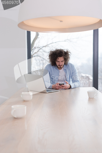 Image of Young casual businessman using smartphone