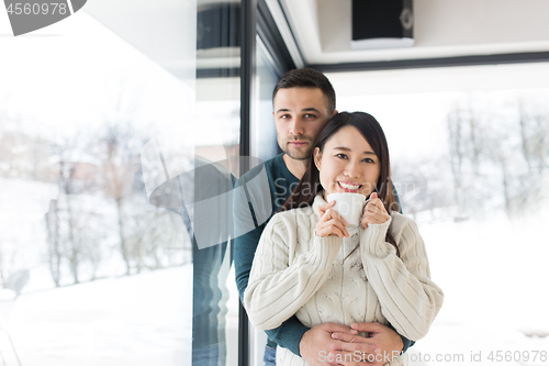 Image of multiethnic couple enjoying morning coffee by the window