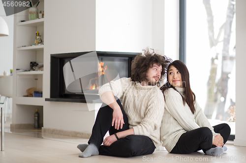 Image of happy multiethnic couple  in front of fireplace