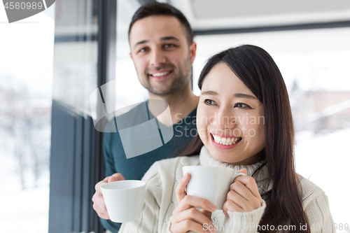 Image of multiethnic couple enjoying morning coffee by the window