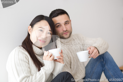 Image of multiethnic couple enjoying morning coffee by the window