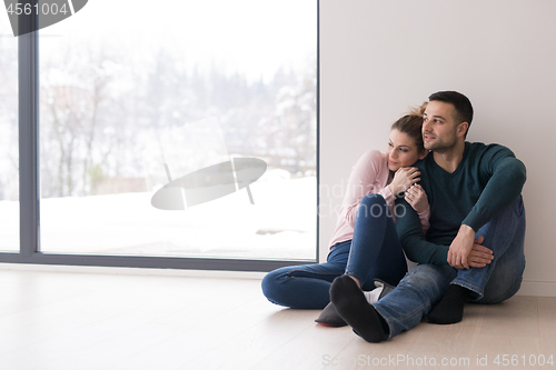 Image of young couple sitting on the floor near window at home