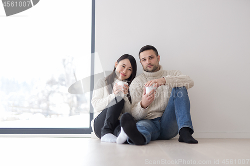 Image of multiethnic couple enjoying morning coffee by the window