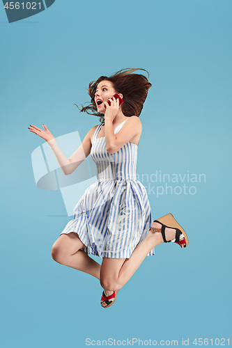 Image of Full length of pretty young woman with mobile phone while jumping