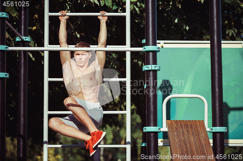 Image of Athlete doing exercises at stadium at park