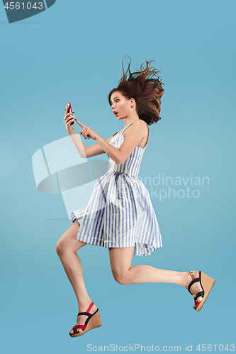 Image of Full length of pretty young woman with mobile phone while jumping