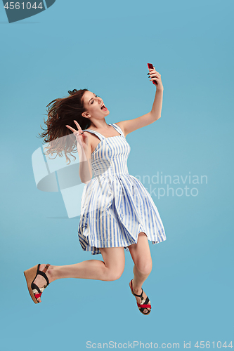 Image of Full length of pretty young woman with mobile phone while jumping