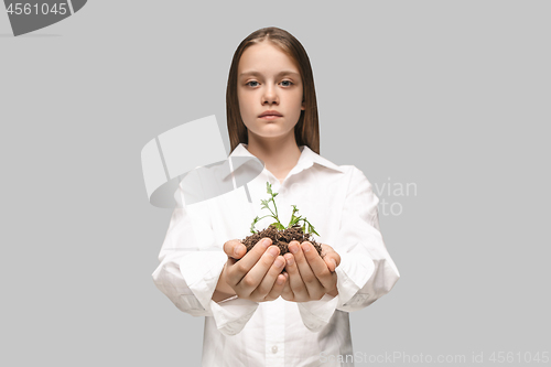 Image of Teen hands with seedlings on gray studio background. Spring concept, nature and care.