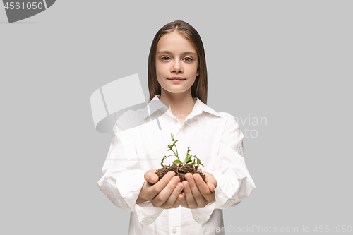 Image of Teen hands with seedlings on gray studio background. Spring concept, nature and care.