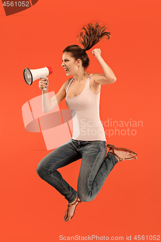 Image of Beautiful young woman jumping with megaphone isolated over red background