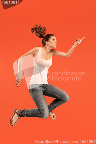 Image of Freedom in moving. Pretty young woman jumping against orange background