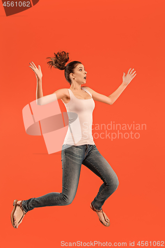 Image of Freedom in moving. Pretty young woman jumping against orange background