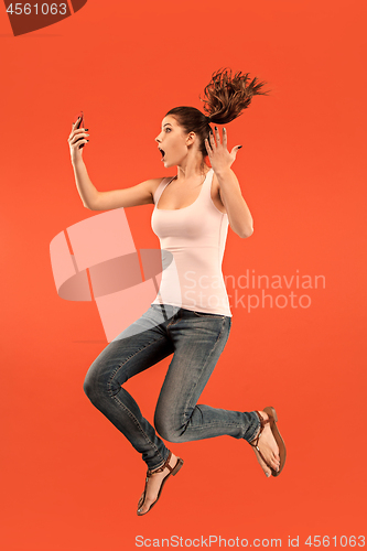 Image of Image of young woman over blue background using laptop computer or tablet gadget while jumping.