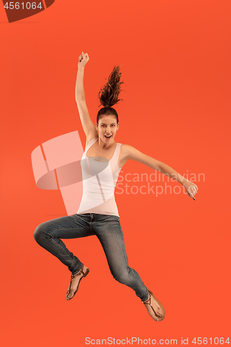 Image of Freedom in moving. Pretty young woman jumping against orange background