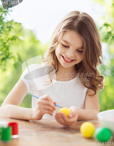 Image of happy smiling girl coloring easter eggs