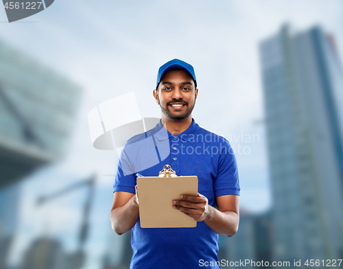 Image of happy indian delivery man with clipboard in blue