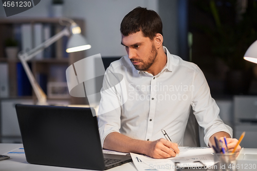 Image of businessman with laptop working at night office