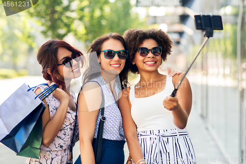 Image of women with shopping bags taking selfie outdoors