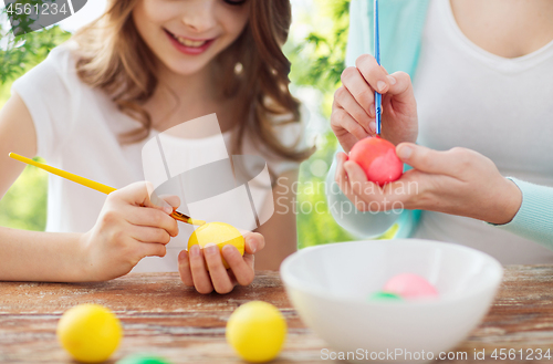 Image of happy smiling girl and mother coloring easter eggs