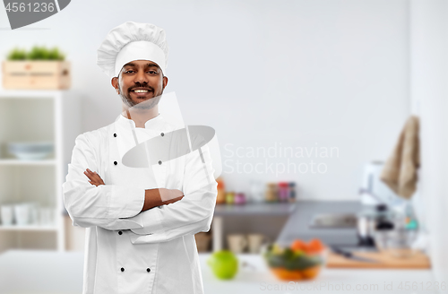 Image of happy male indian chef in toque at kitchen