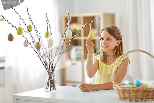 Image of girl decorating willow by easter eggs at home