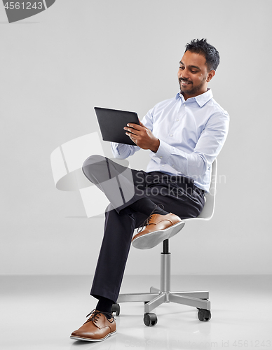 Image of indian businessman with tablet pc on office chair