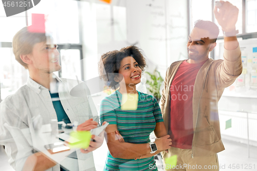 Image of happy creative team at office glass board