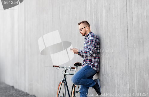 Image of hipster man in earphones with smartphone and bike