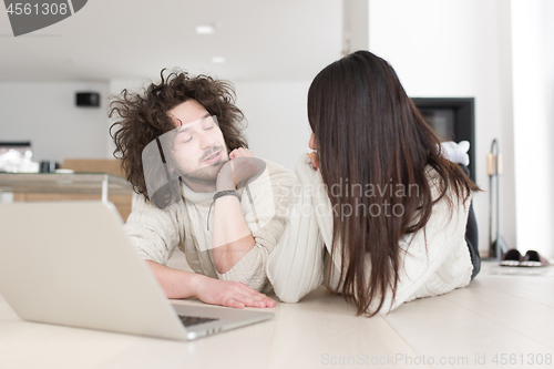 Image of young multiethnic couple using a laptop on the floor