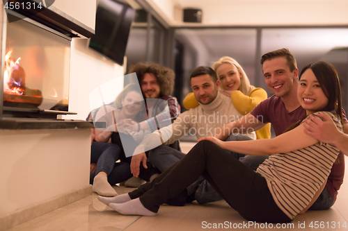 Image of multiethnic couples sitting in front of fireplace