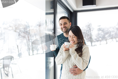 Image of multiethnic couple enjoying morning coffee by the window